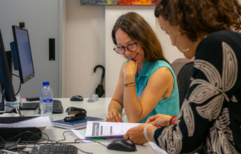 Dos mujeres revisando un documento juntas en un escritorio de oficina